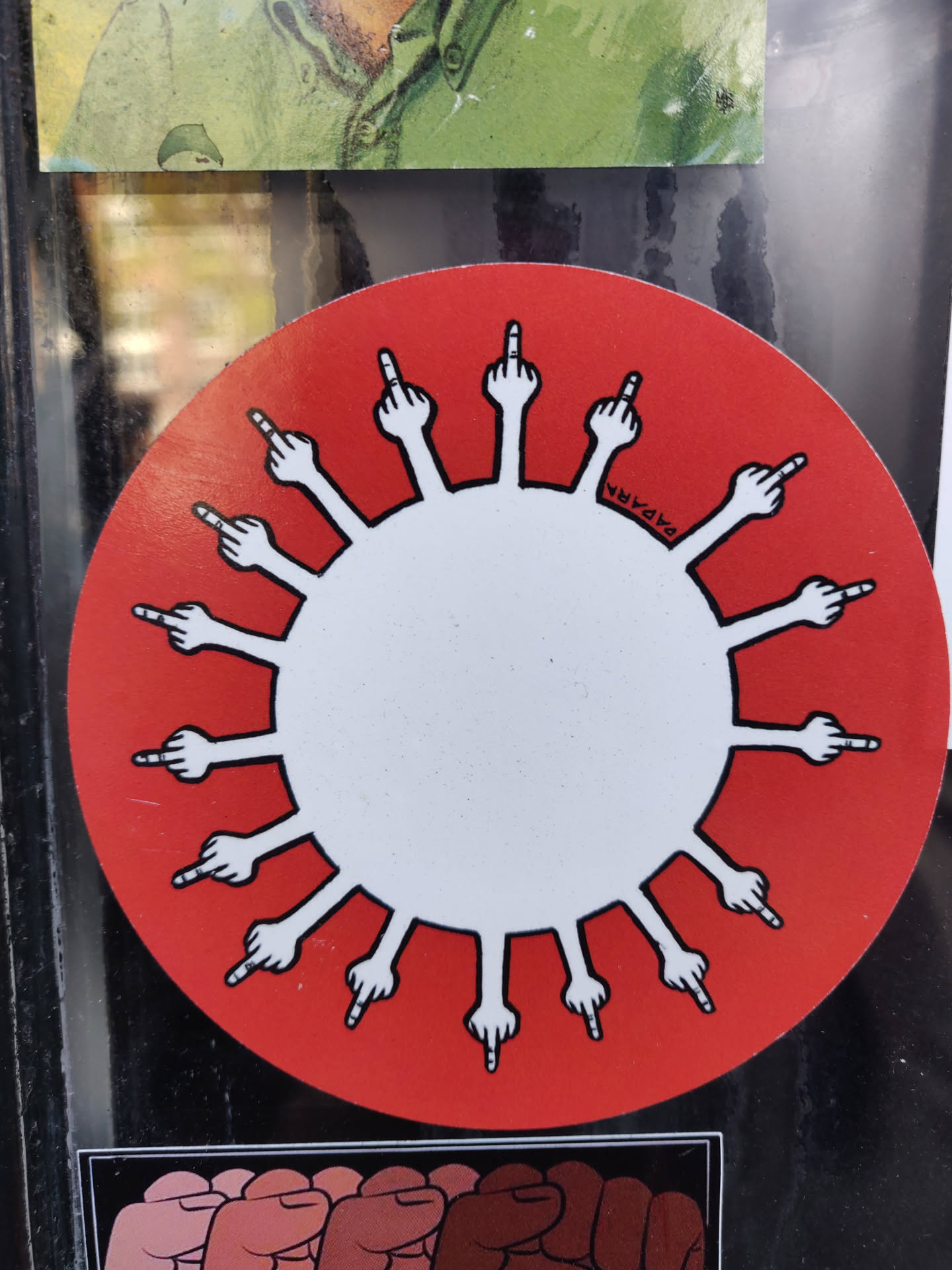 Round sticker featuring a stylized virus with each spike being a middle finger.  The background is red and the virus is white.  A small signature is visible in the center, it seems to say "2424MA".