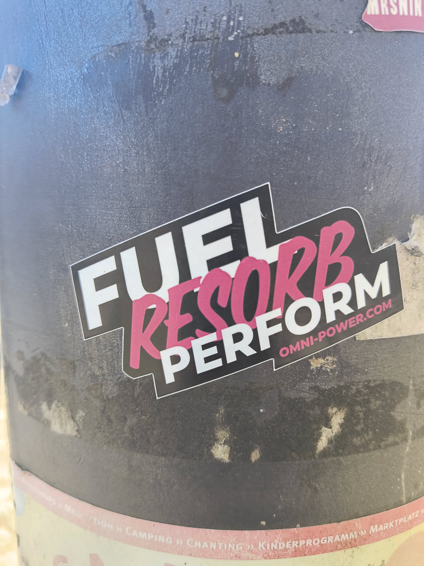 A sticker with the text "FUEL RESORB PERFORM" is attached to a gray pole. The word "RESORB" is printed in pink.