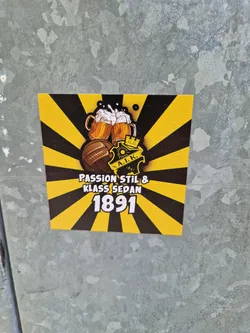 A yellow and black sticker with two beer steins, a soccer ball and the text "Passion Stil & Klass Sedan 1891".