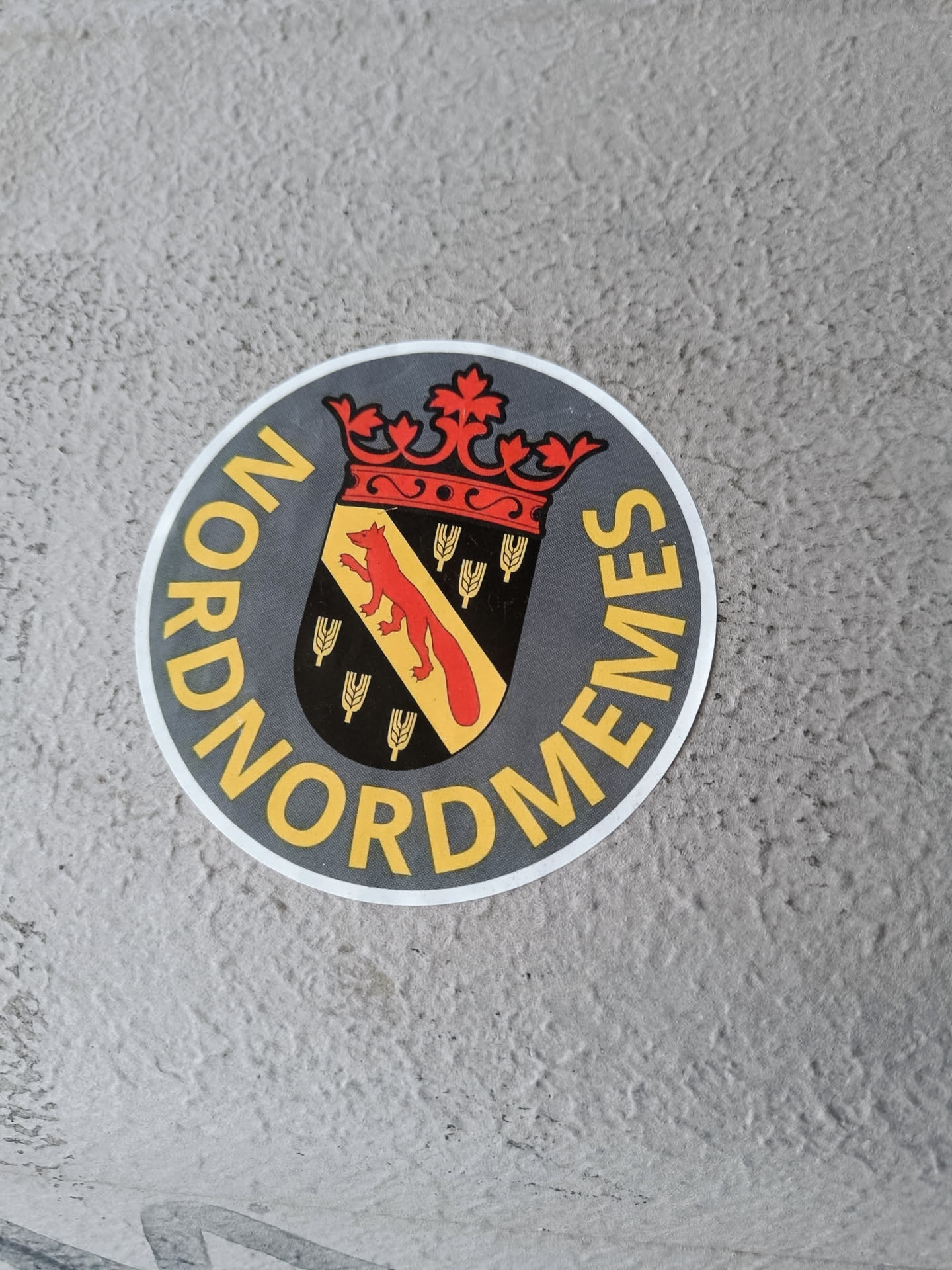 Round sticker with a coat of arms featuring a fox and wheat, surrounded by the word NORDMEMES. 