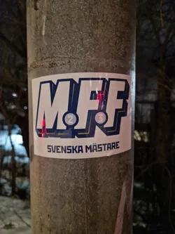 A sticker featuring the MFF logo and the text "Svenska Mästare" (Swedish Champions). The logo appears to be a stylized representation of the letters MFF with numbers 2 and 3 incorporated into the design. 