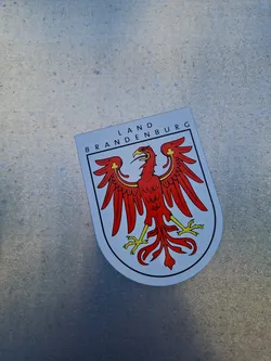 A sticker featuring the coat of arms of Brandenburg, Germany. The sticker is white with a red eagle in the center.  The text "LAND BRANDENBURG" is visible at the top.