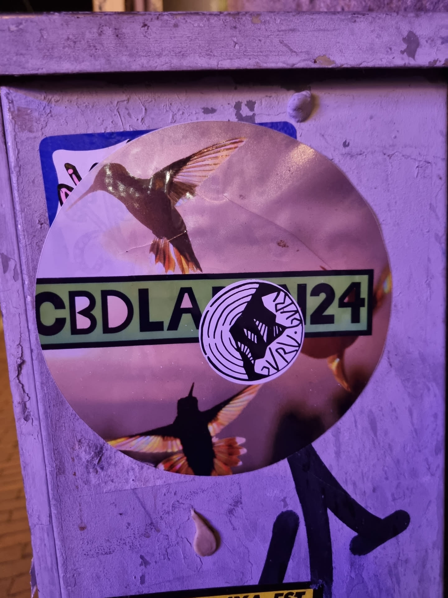 Round sticker featuring two hummingbirds in flight.  There's a smaller circular sticker on top with a graphic of a fist and the text "GRVL24". A banner reads "CBDLA".