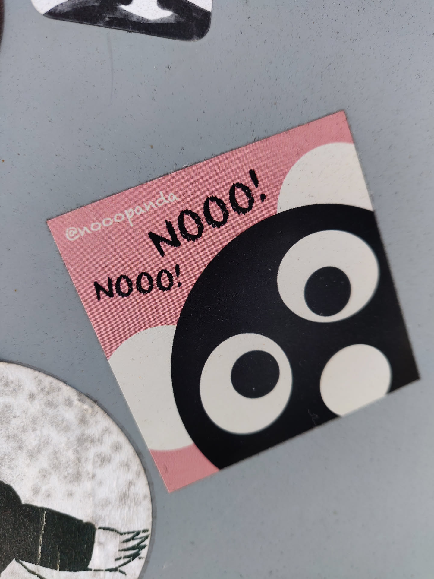 A square sticker featuring a cute cartoon character with big eyes. The character is black and white, set against a pink background. The text "NOOO!" is written in black. The sticker also has the Instagram handle @noooPanda in the corner.