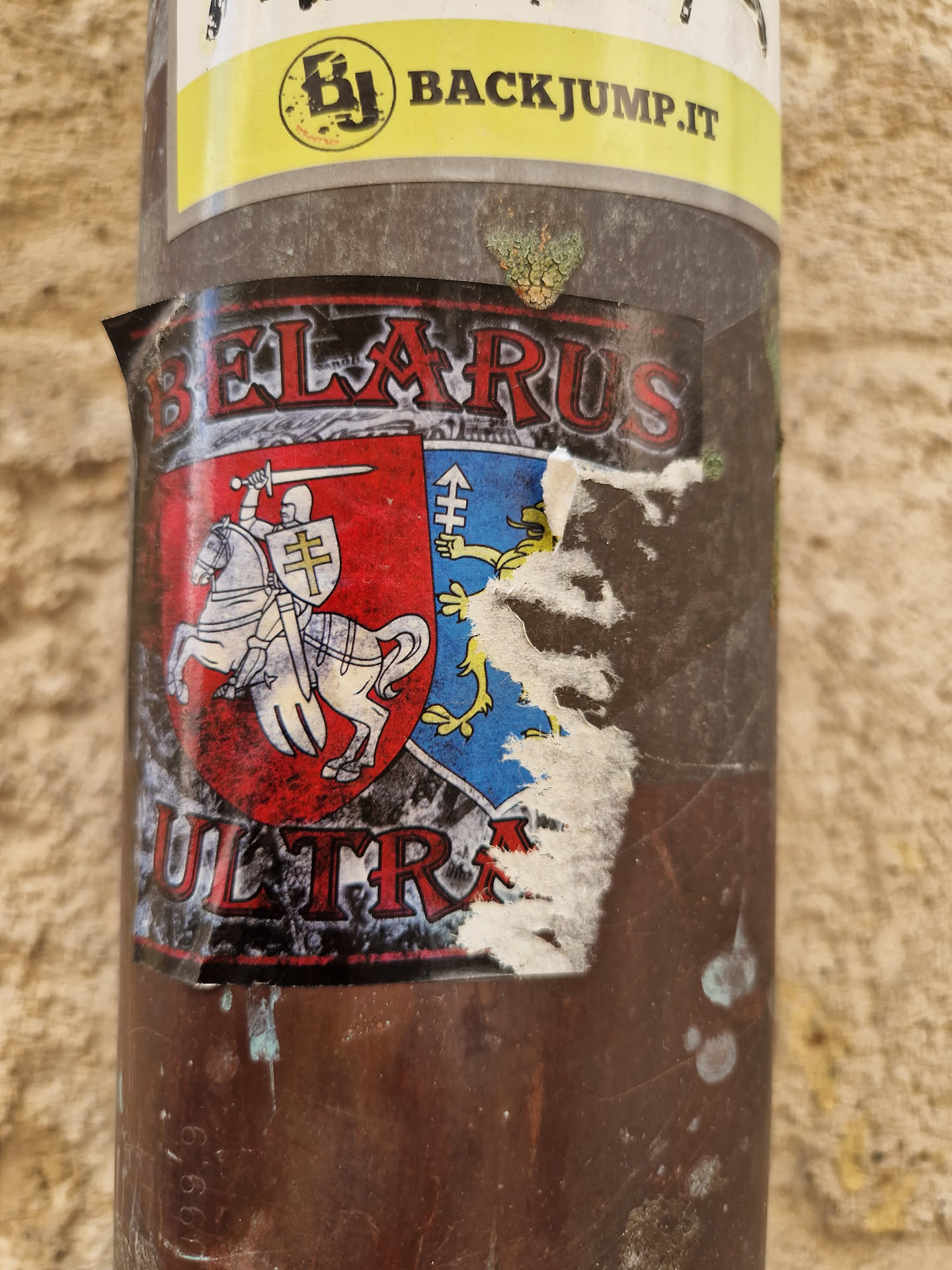 A sticker featuring a coat of arms with a knight on a horse and the word "BELARUS" above and "ULTRA" below. The sticker is partially damaged.