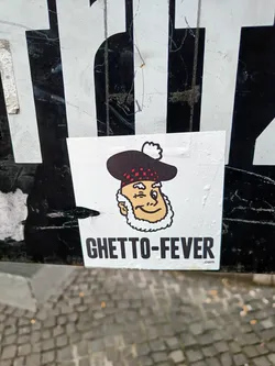 A sticker featuring a cartoon man in a tam o' shanter, winking, with the text "GHETTO-FEVER.com" below. 