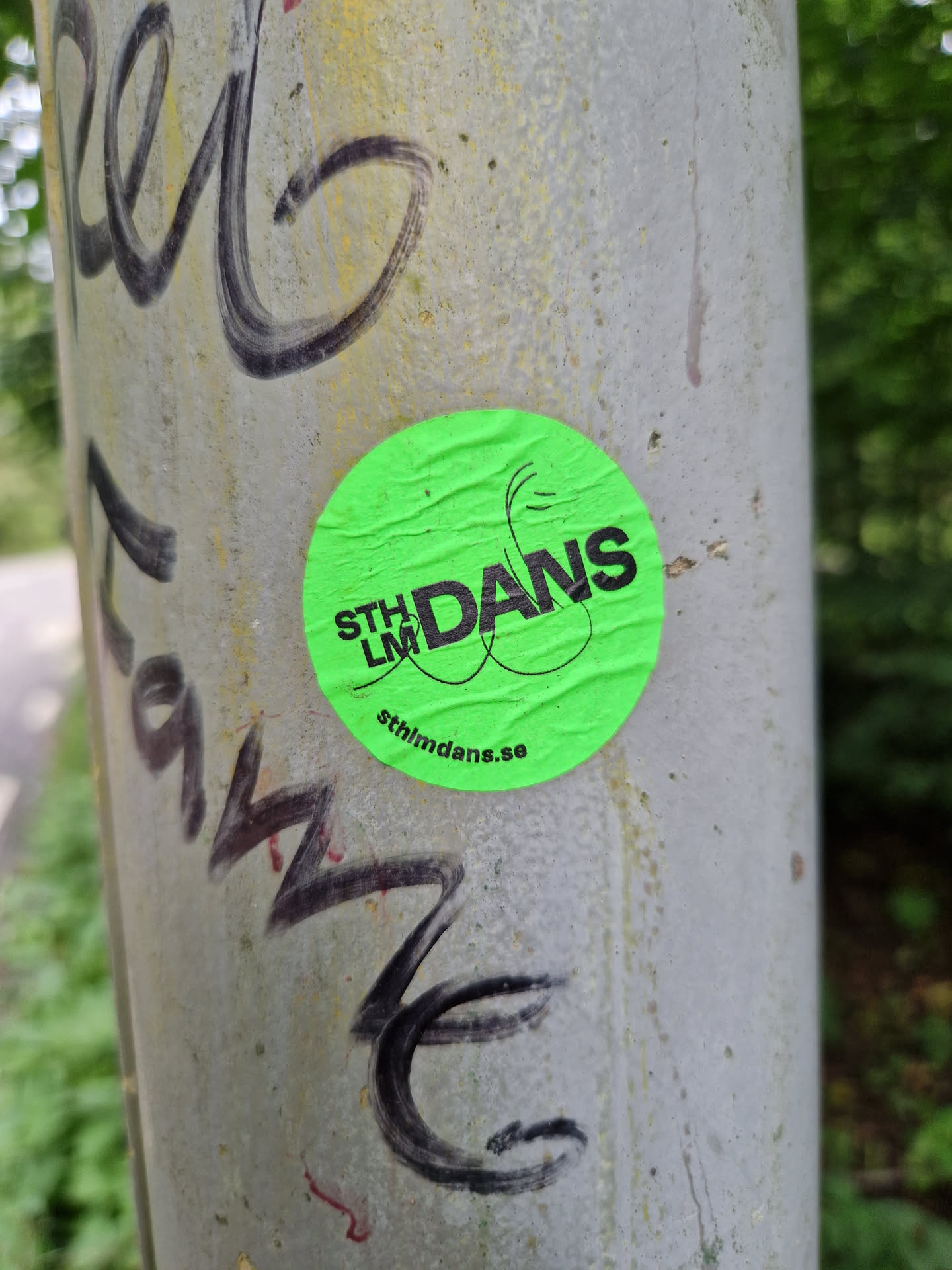 A bright green round sticker with black text.  The main text says "STHLM DANS" with a stylized graphic element. At the bottom, a website is visible: sthlmDans.se