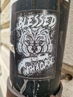 Black and white sticker featuring a wolf's head and the text 'Blessed with a curse'.  The sticker also includes a Facebook link at the bottom.