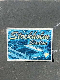 A sticker depicting an illustration of Stockholm Stadium. The sticker is predominantly blue, featuring a stylized image of the stadium and the text 'Stockholm Stadium' in a vintage-inspired font.