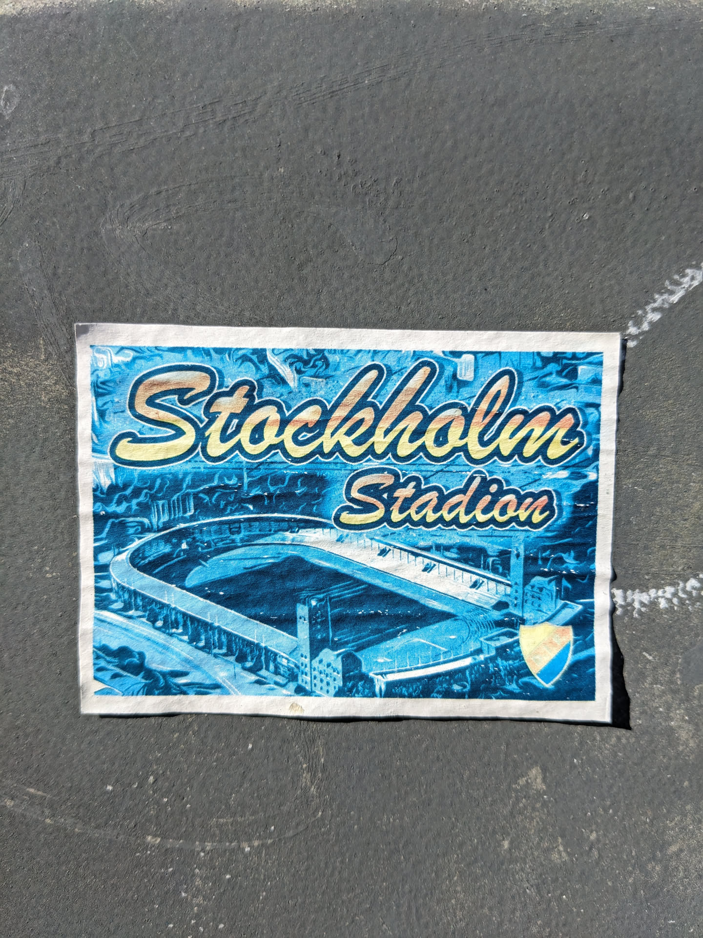 A sticker depicting an illustration of Stockholm Stadium. The sticker is predominantly blue, featuring a stylized image of the stadium and the text 'Stockholm Stadium' in a vintage-inspired font.