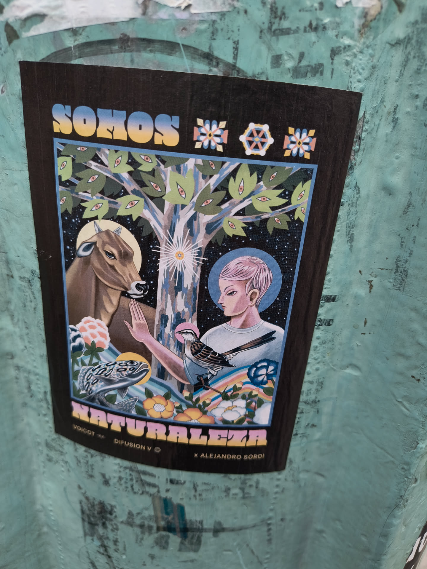 Sticker featuring a colorful illustration of a person interacting with nature, including a cow, a tree with eyes, and a bird. The text 'Somos Naturaleza' is prominently displayed, along with artist credits 'VOCOT x DIFUSION V © x ALEJANDRO SORDO'. The style is psychedelic and mystical.
