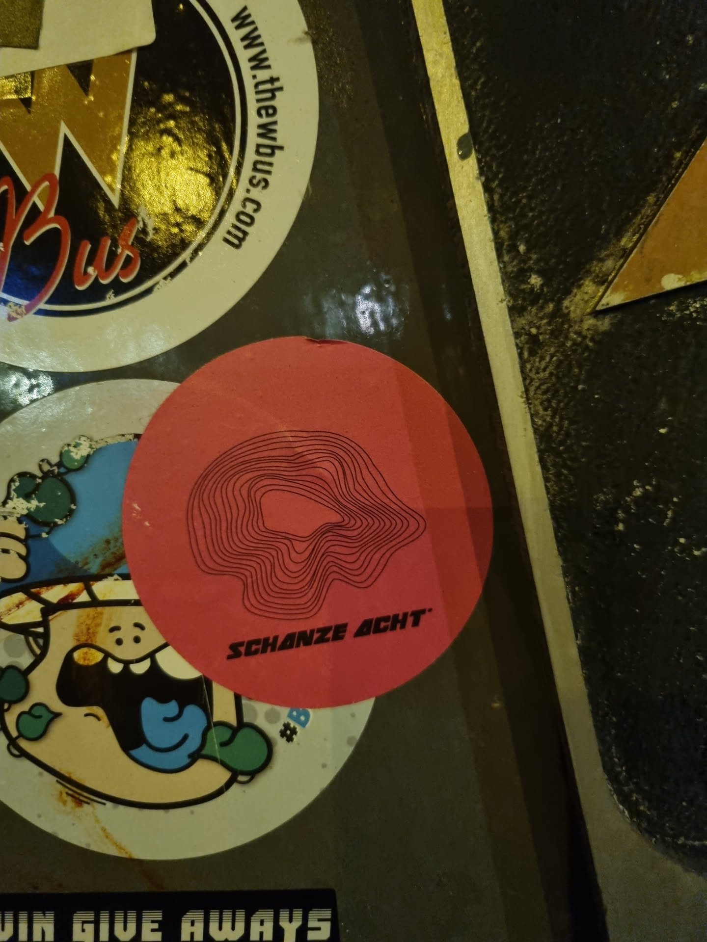 A pink round sticker with a black topographic design and the text "SCHANZE ACHT" printed on it.