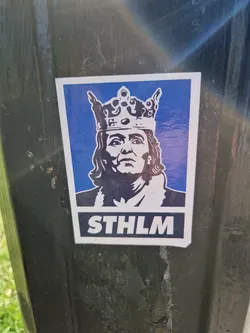 A sticker featuring a stylized portrait of a king wearing a crown, set against a blue background. The text "STHLM" is prominently displayed at the bottom, representing Stockholm.