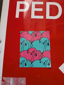A square sticker featuring a dense, repeating pattern of stylized, rounded shapes, reminiscent of bubble letters or graffiti tags. The primary colors are bright pink and a light teal/aqua blue, with all shapes outlined in black. Several elements within the pattern include small black 'drips' or teardrop shapes, adding to the graffiti aesthetic. The pattern fills the entire sticker, creating a continuous and dynamic design. The sticker is placed on a glossy red surface.