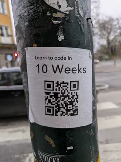 A sticker on a pole with a QR code leading to a 10-week coding course.