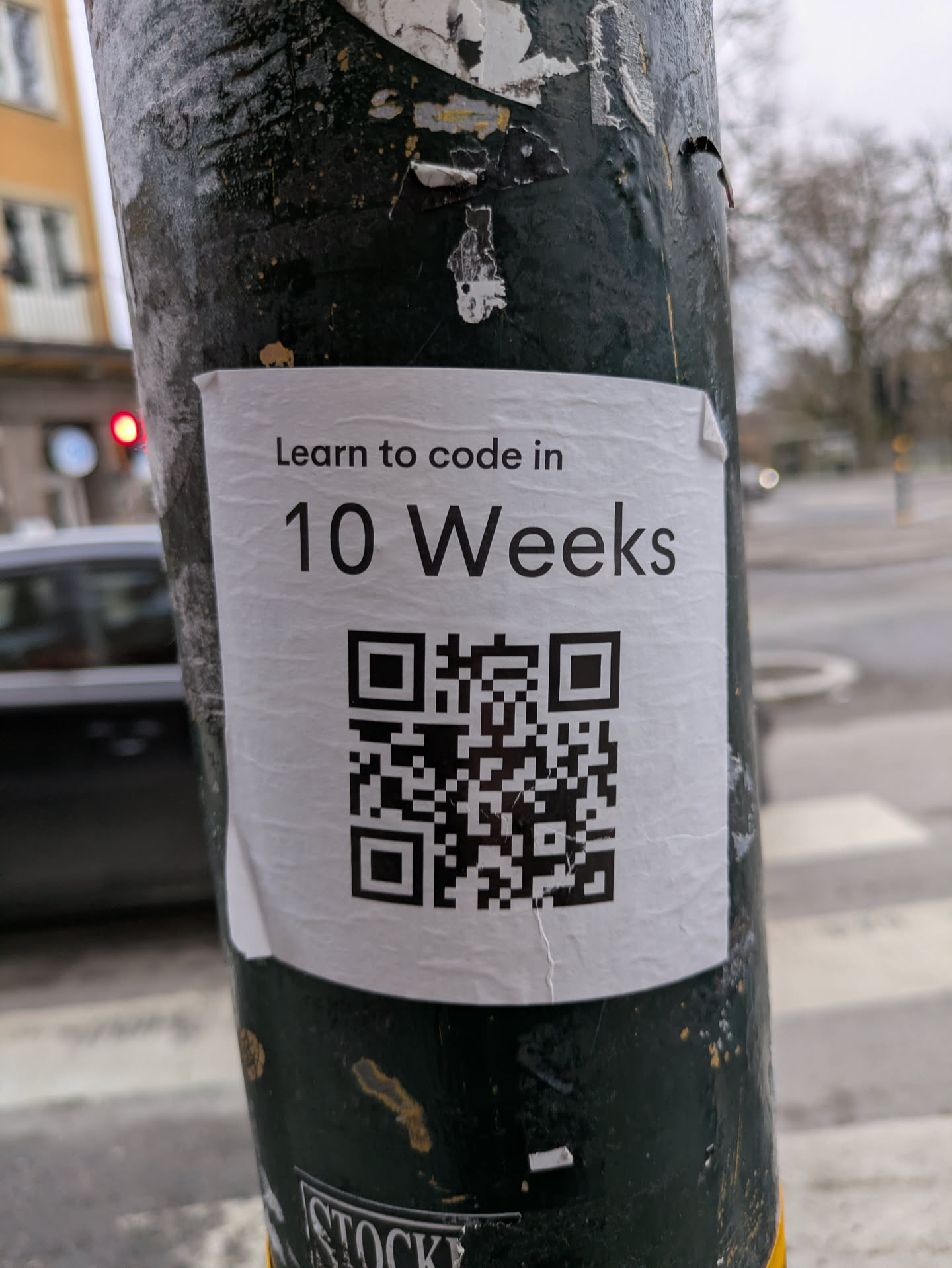 A sticker on a pole with a QR code leading to a 10-week coding course.