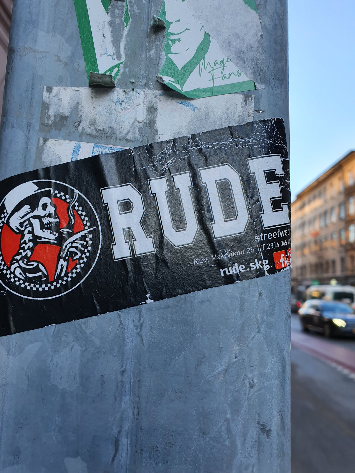 A black and white sticker with the word "RUDE" prominently displayed.  It features a circular logo with a skull wearing a hat.  Smaller text indicates an address and website. The style is reminiscent of punk or rockabilly aesthetics. 