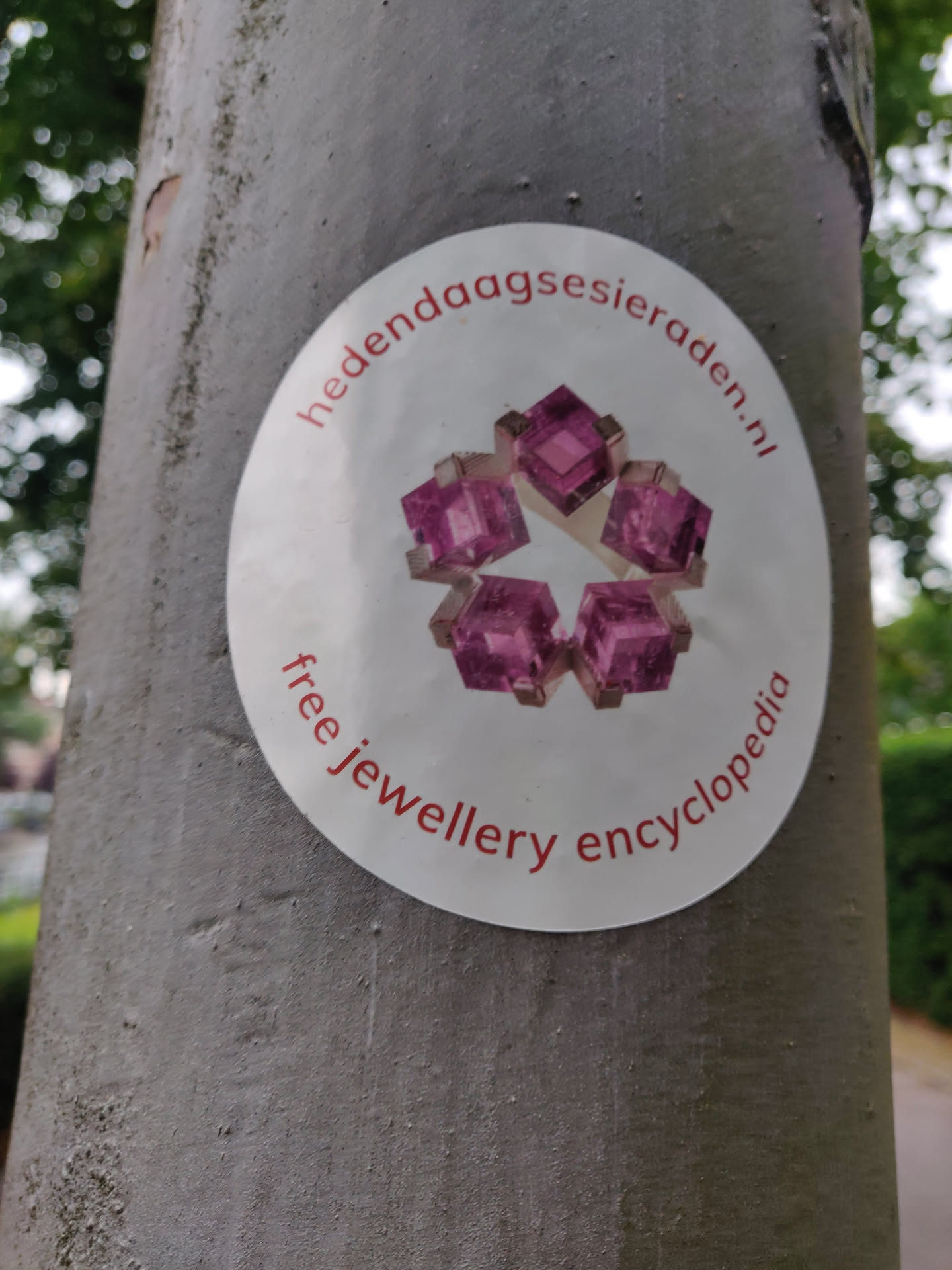Round sticker with a picture of pink gemstones in the center. The text hedentijdagsieraaden.nl is visible at the top.  The text "free jewellery encyclopedia" is visible at the bottom.