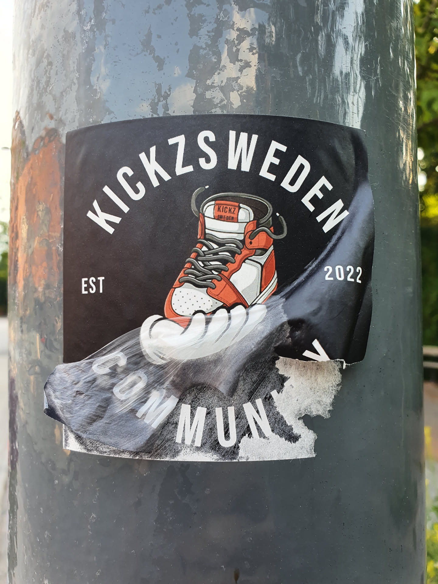 A sticker featuring a sneaker illustration with the text KICKZSWEDEN, Est, and 2022. The bottom part of the sticker is peeling off.