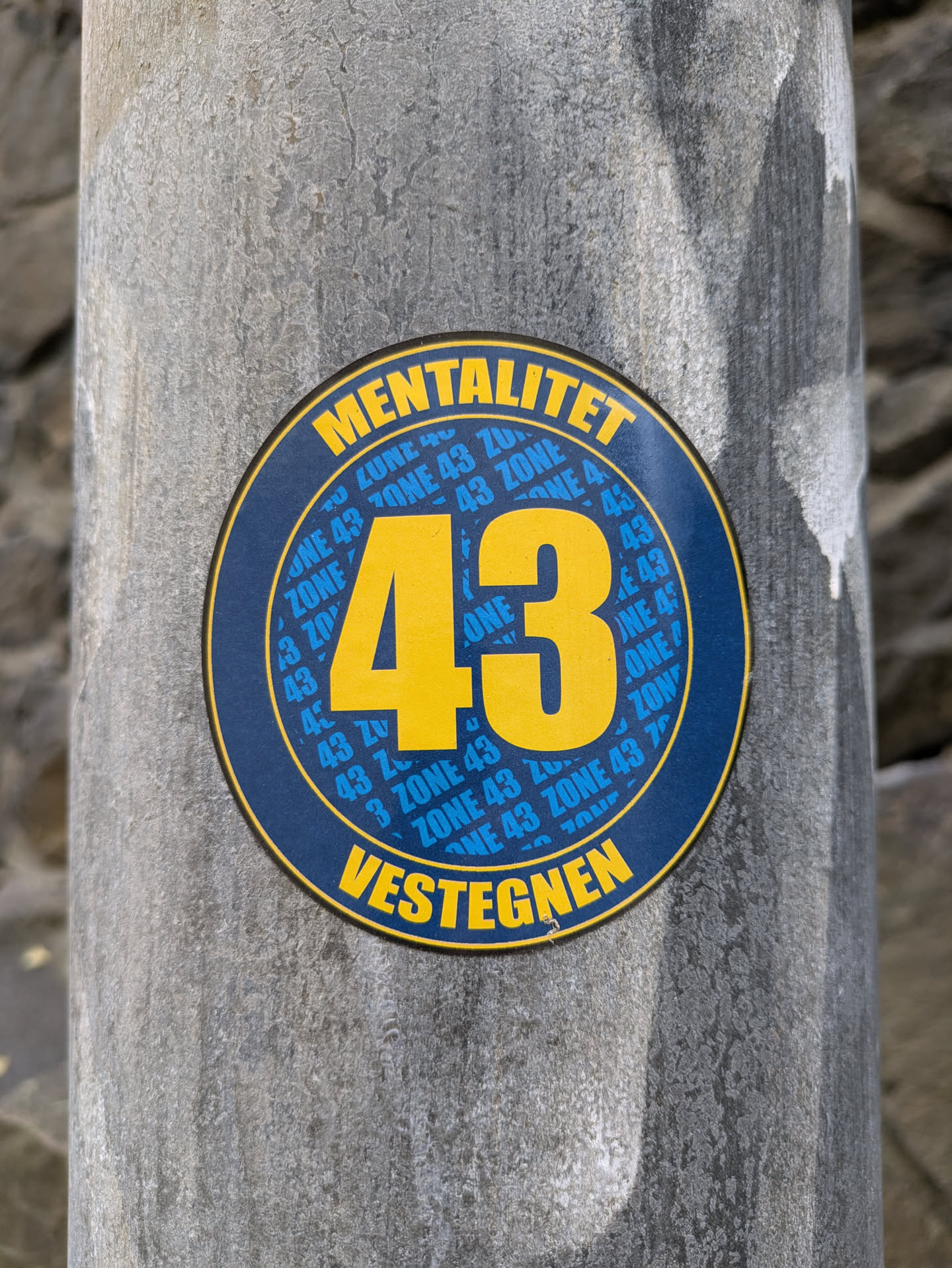 Round sticker with the number 43 in the center. The words 'MENTALITET' and 'VESTEGNEN' are written at the top and bottom respectively. The number 43 and the words 'ZONE 43' are repeated around the number 43 in smaller font. 