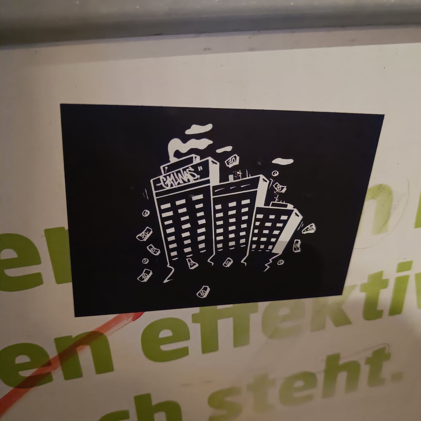 Black and white sticker depicting three buildings with money falling from them. The word Gangs is written on the top of one of the buildings. It has a dark and gritty style.