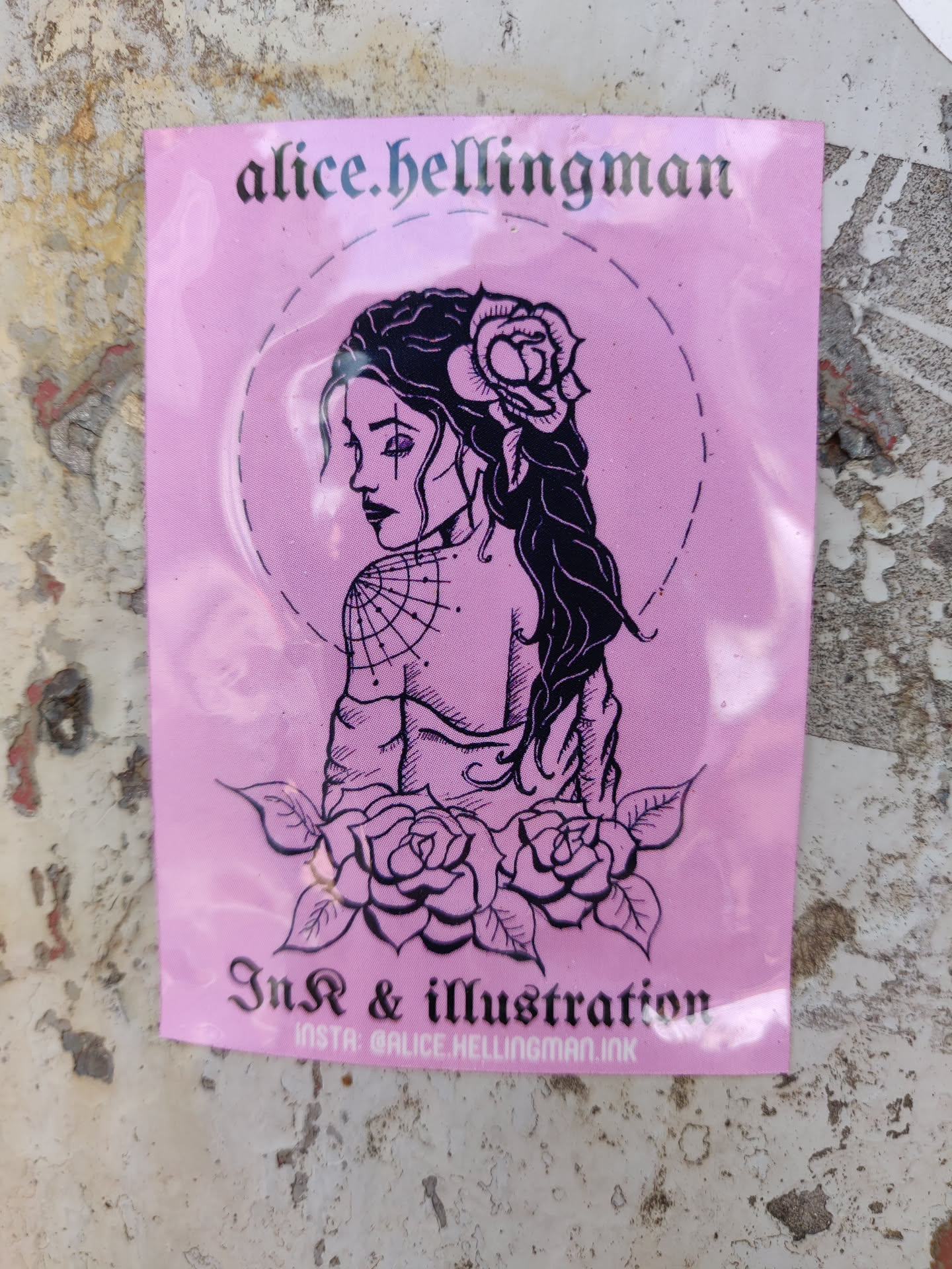 Pink sticker featuring a line art illustration of a woman with a rose in her hair, looking over her shoulder. She has a spiderweb on her back. Below her are roses and leaves. The artist's name and social media handle are included. 