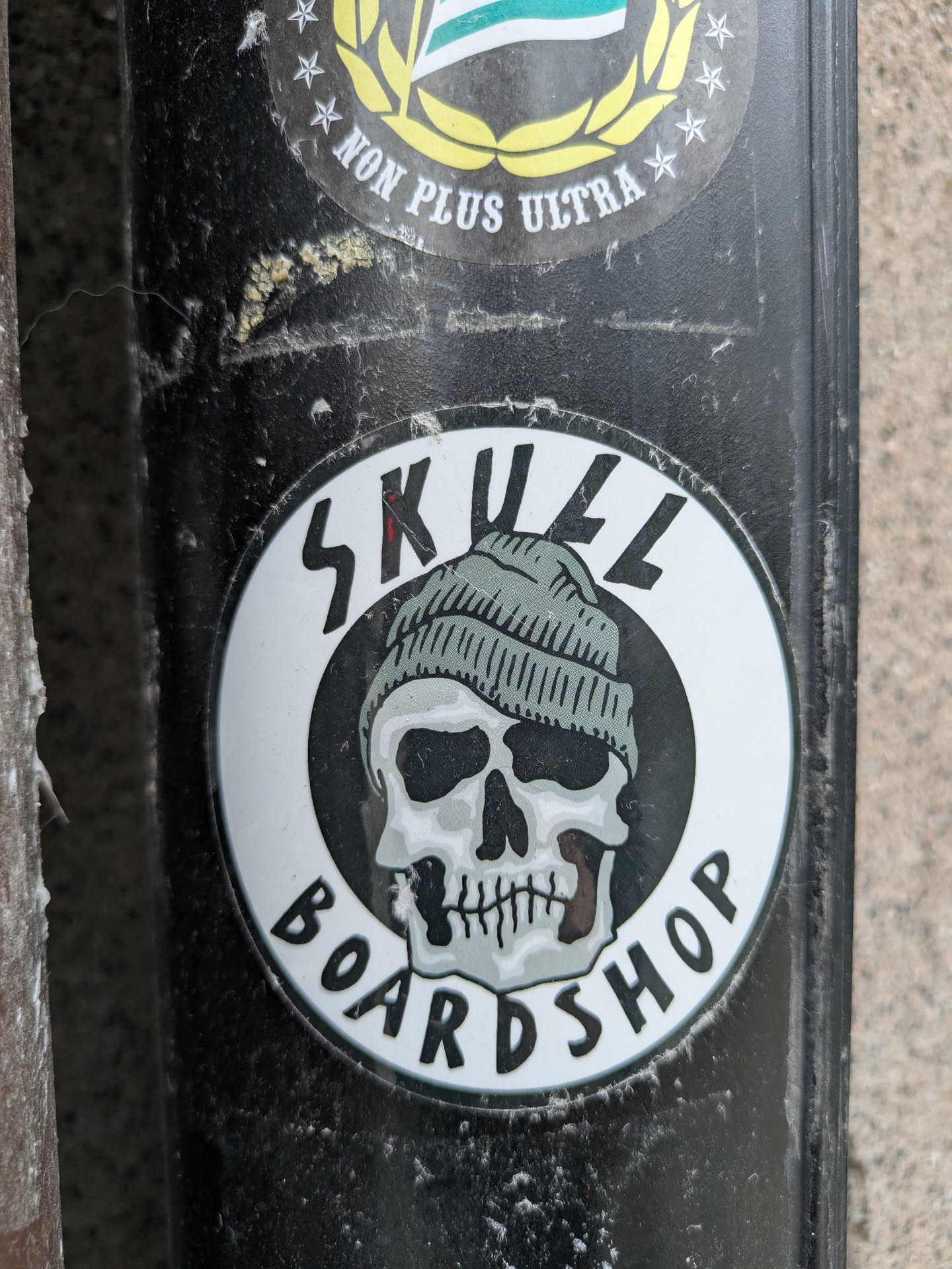 A round sticker with a skull wearing a beanie in the center. The text "SKULL BOARD SHOP" is written around the skull. 