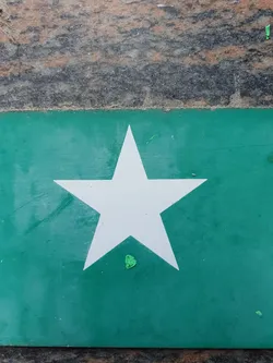 This sticker showcases a minimalist design with a white five-pointed star as the focal point against a teal green backdrop.  The color contrast is quite effective. The sticker itself appears to be made of a slightly textured material.