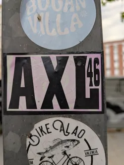A rectangular sticker with a black border. It contains the word 'AXL' in large, bold, black letters, followed by the number '46' in a smaller font size. The background has a pink and white swirling pattern.