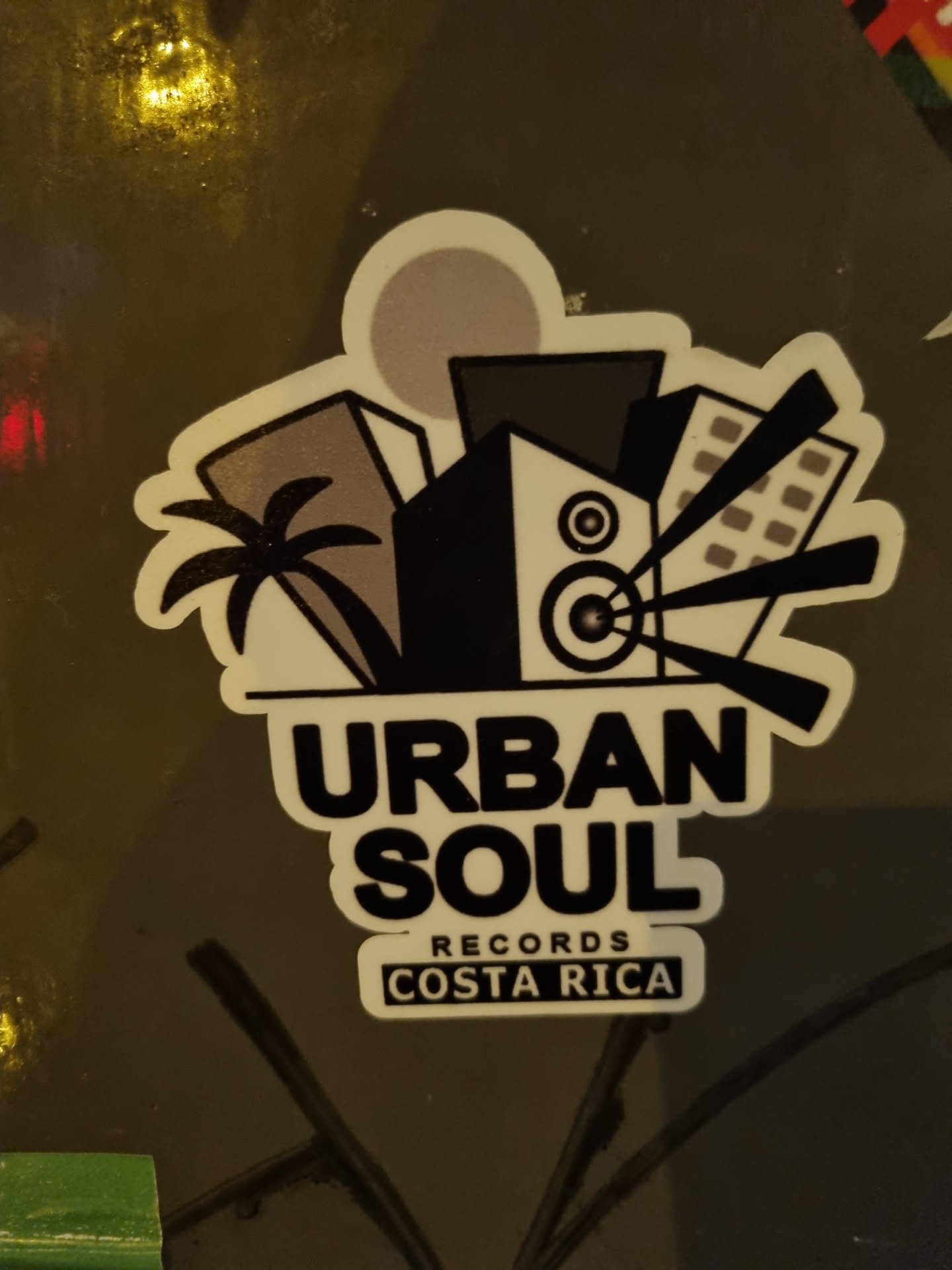A sticker featuring the logo for Urban Soul Records, located in Costa Rica. The logo depicts a stylized cityscape with palm trees, a speaker, and radiating sound waves.  The text 'Urban Soul' is prominently displayed, with 'Records' and 'Costa Rica' in smaller text below.
