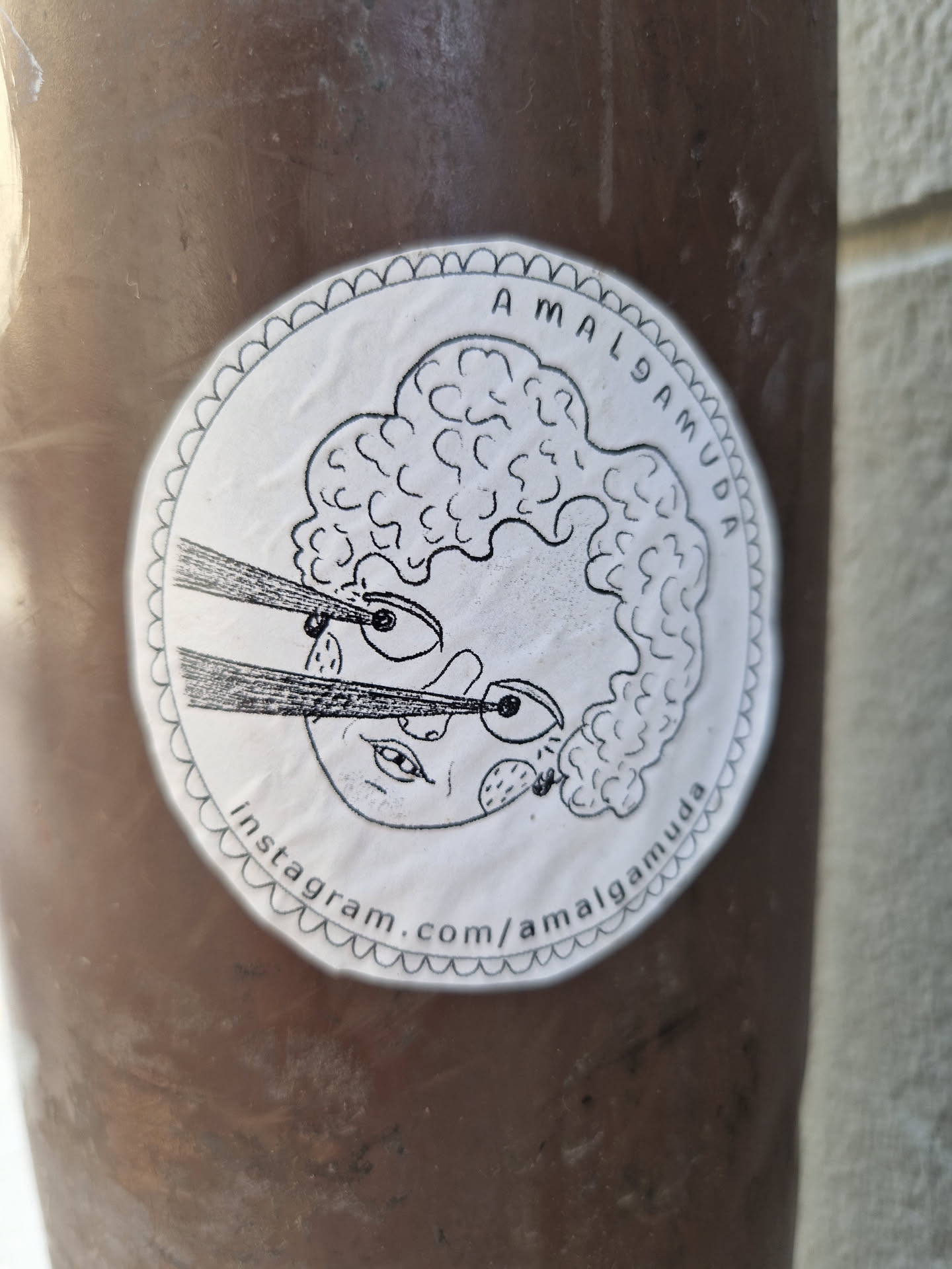 This round sticker showcases a hand-drawn illustration of a person with curly hair, expressive eyes, and what appears to be a ray of light or a whisker emerging from their face. The style is whimsical and slightly surreal. The artist's Instagram handle is printed at the bottom of the sticker.