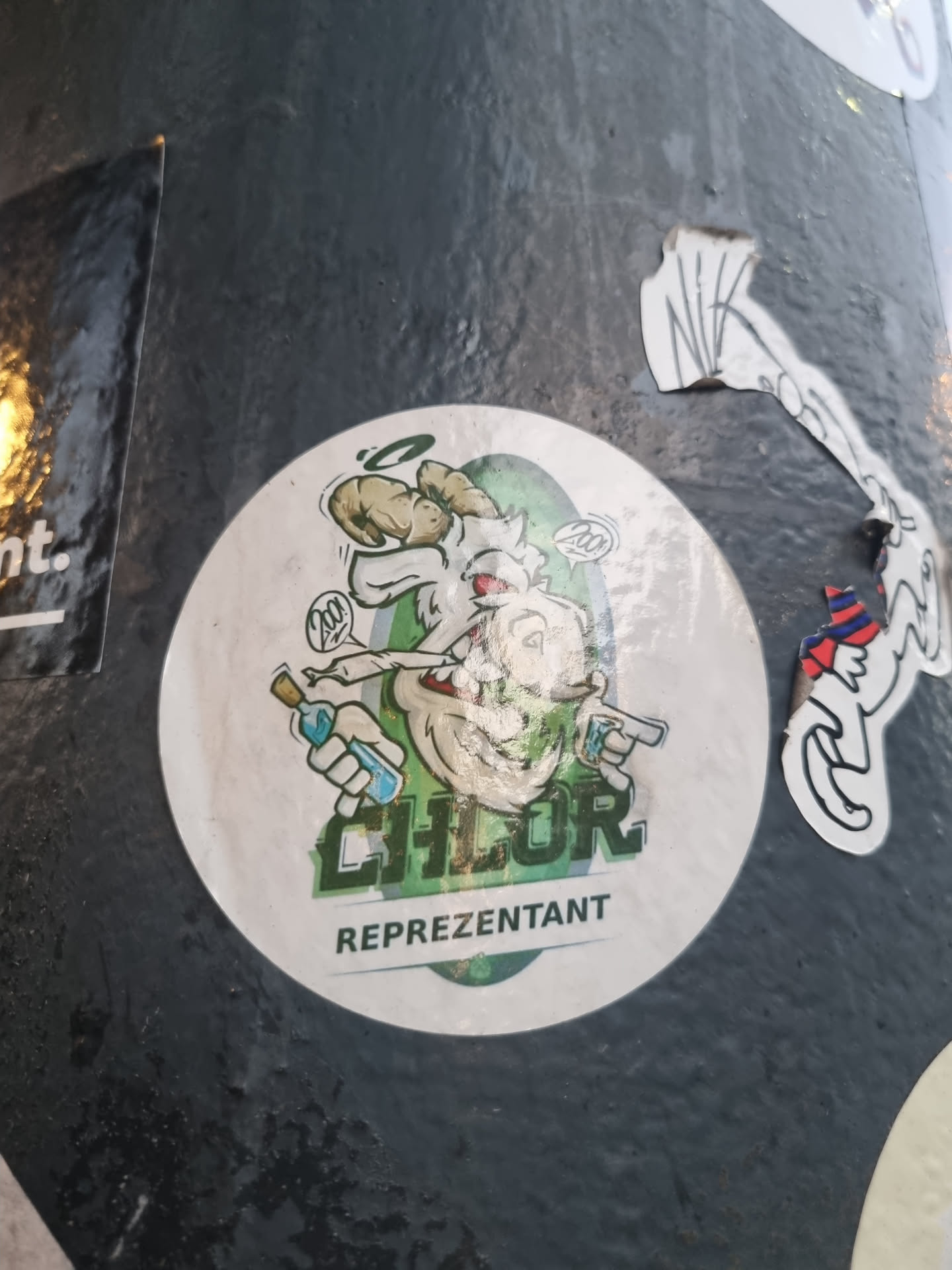 Round sticker featuring a cartoon goat-like creature holding a bottle and a gun. The creature has horns, a mischievous expression, and is depicted in shades of green and white. The text "CHLOR" is prominently displayed above the word "REPREZENTANT".