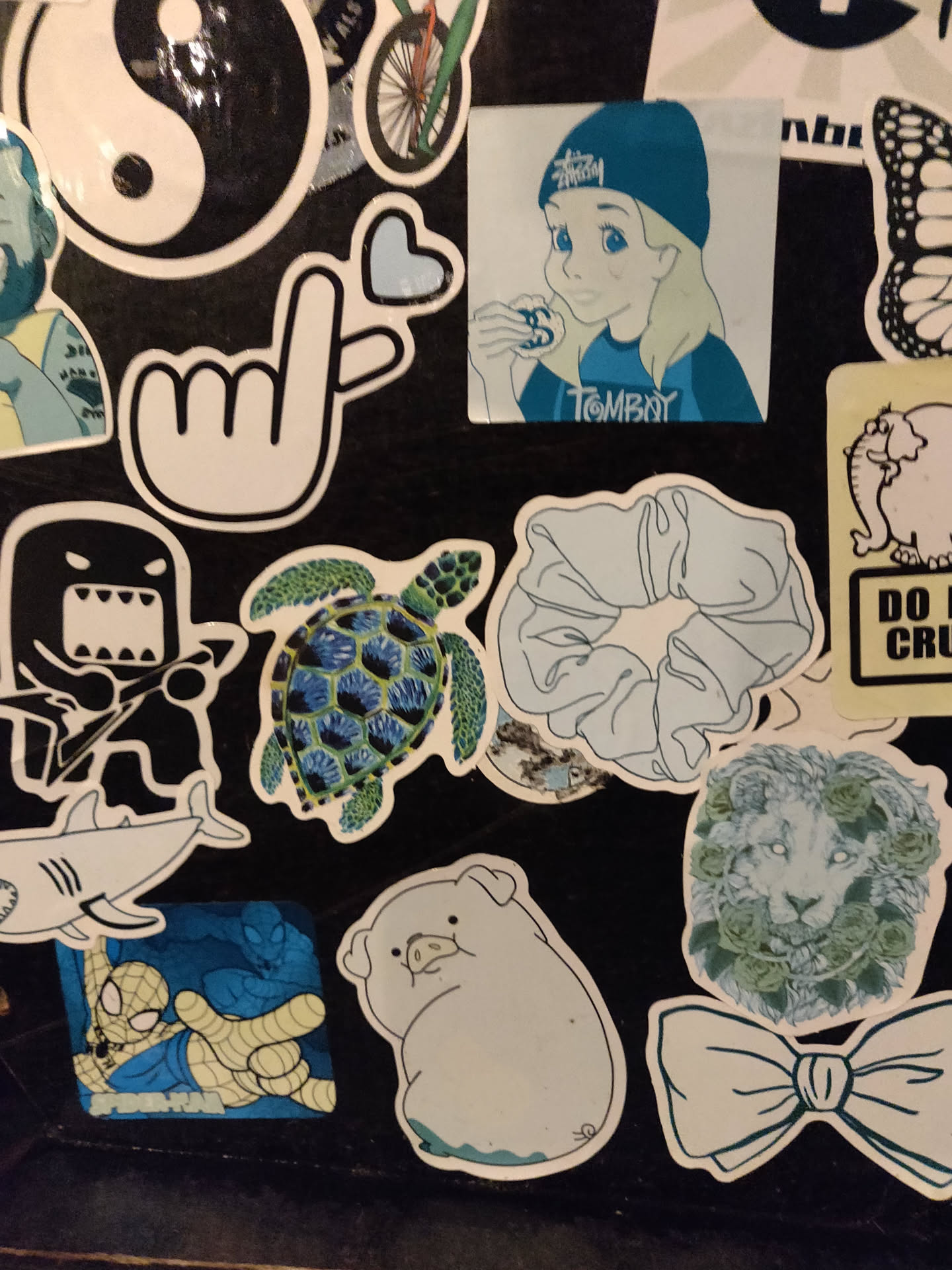 Collection of stickers in varying light blue shades.  The central sticker shows a stylized cartoon girl with light blonde hair wearing a blue beanie.  Other stickers include a sea turtle with a detailed shell, a hair scrunchie, a simple pig illustration, and a lion's face surrounded by leafy elements. All stickers share a consistent light blue color palette.