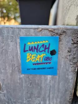 A blue sticker with the text "Lunch Beat GBG" in yellow and purple stylized lettering.  Below it, in smaller text, it says "Not your ordinary lunch".