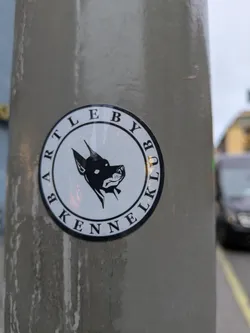 Round sticker with a black and white illustration of a dog's head in profile. The text 'Bartleby Kennel Club' circles the image.