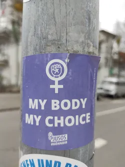 A purple sticker with a feminist symbol and the text "MY BODY MY CHOICE". It also includes the logo and hashtag of a group called JUSOS.