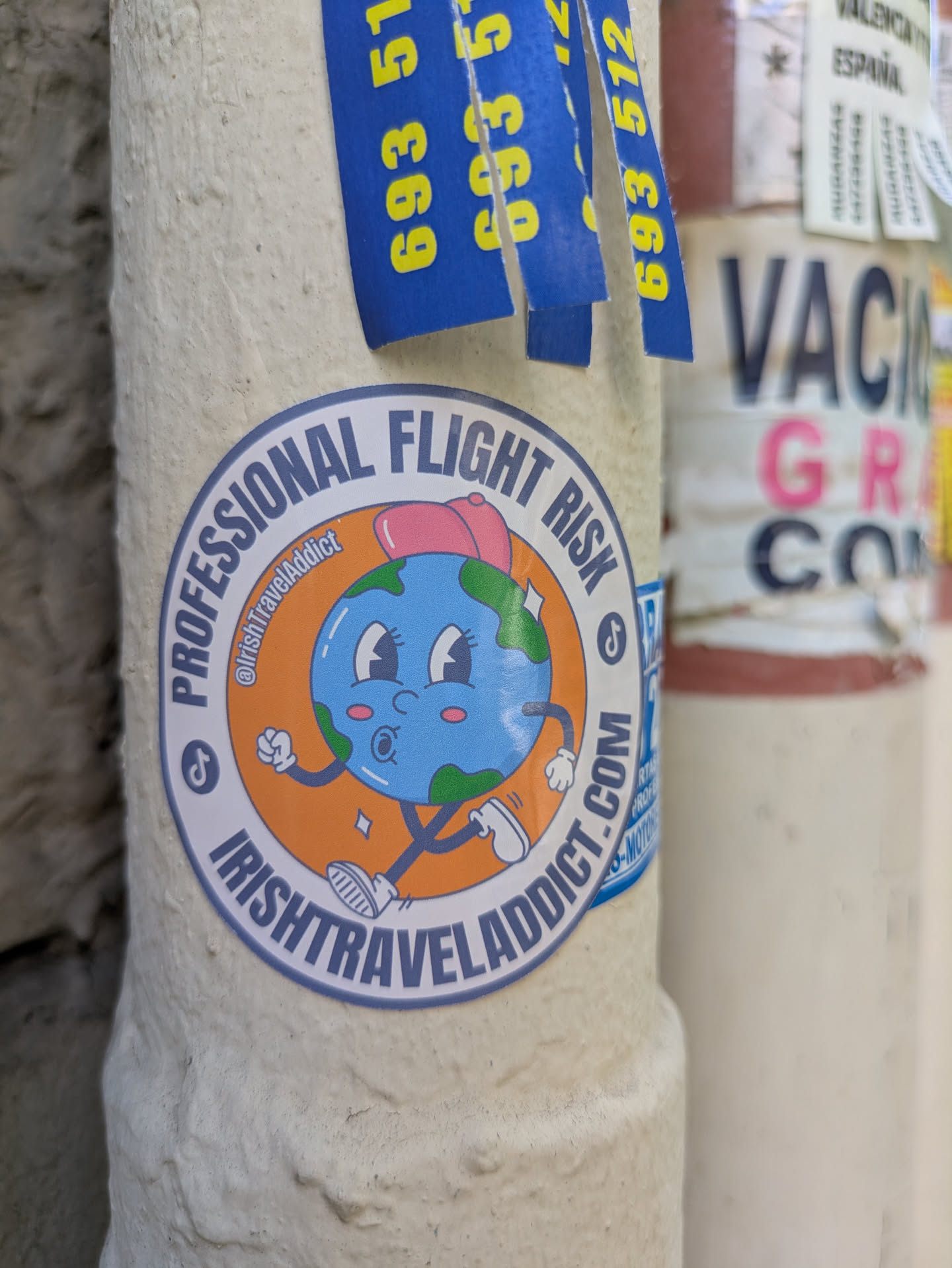 This vibrant sticker showcases a cartoon depiction of Earth, complete with a pink bow, blushing cheeks, and expressive eyes. The Earth figure is playfully walking with cartoon shoes. The sticker is encircled with the text 'PROFESSIONAL FLIGHT RISK' at the top and 'IRISHTRAVELADDICT.COM' at the bottom. The design is completed with social media icons for TikTok and a username @IrishTravelAddict