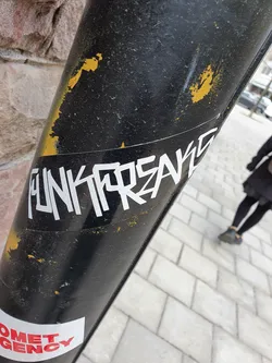 A white sticker with the text "Funkforskare" in a stylized, graffiti-like font on a dark surface. The sticker shows some signs of wear.