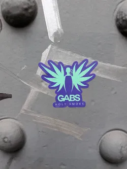 Street sticker A die-cut sticker with a deep purple/indigo base and mint green graphics. The central icon features a stylized silhouette of a person smoking, flanked by cannabis leaves spread out like angel wings. Below the illustration, the word 'GABS' is displayed in bold rounded lettering, followed beneath by the phrase 'HOLY SMOKE' in a smaller sans-serif font.