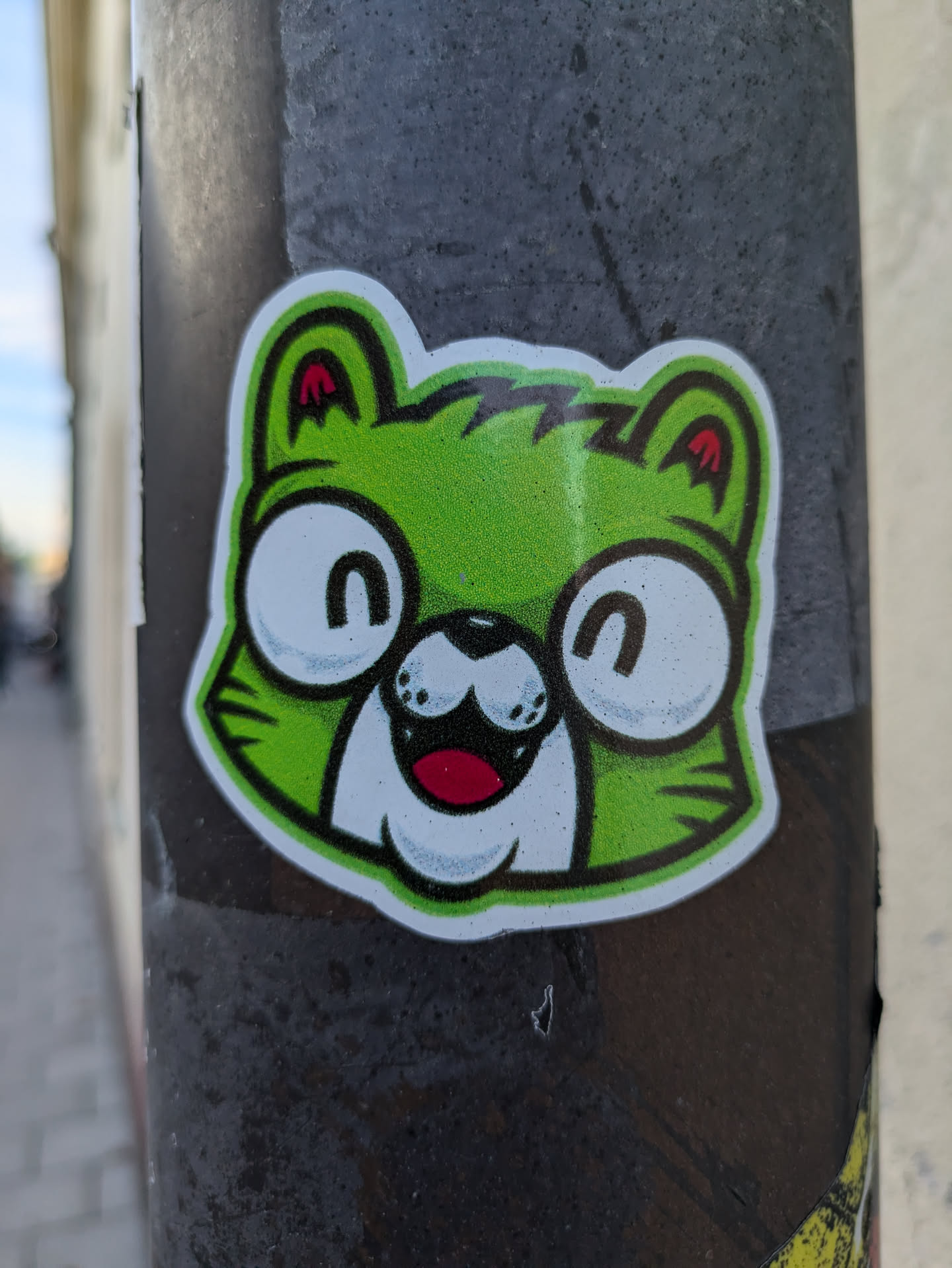 A vibrant green creature with a cheerful expression adorns this sticker. Its simplistic yet expressive design makes it visually appealing.