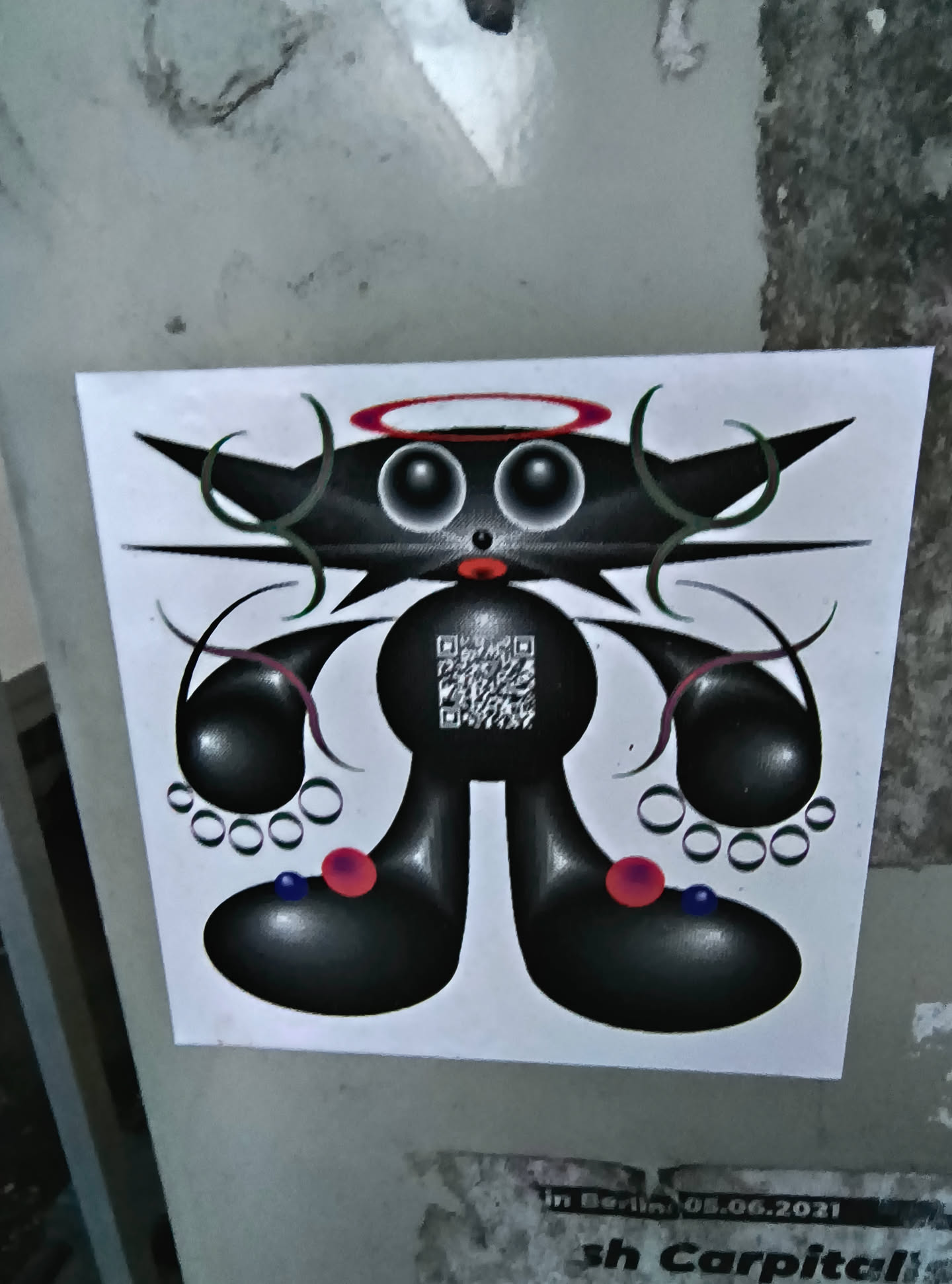 The sticker features a unique cartoonish character rendered in black and white with touches of red and blue. The character has a round body, large eyes with a red halo above, and horns that appear like sharp curves. The limbs are bulbous and adorned with circles resembling beads. A QR code is placed on the character's body. The style is reminiscent of surrealist art.