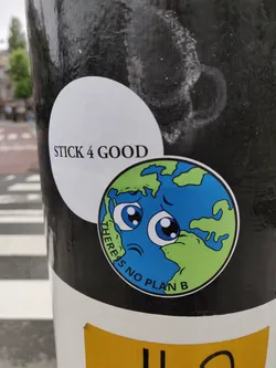 A round sticker with a cartoon illustration of the earth with a sad face. The text 'There is no plan B' is written around the illustration. Another sticker is on top of this one, with the text 'Stick 4 Good'.
