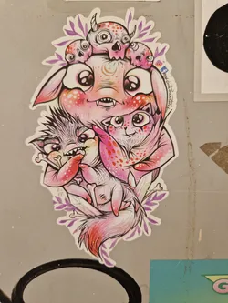 A sticker featuring a pink monster with smaller monsters on its head, and two cute animals in its arms. The style is cartoonish and colorful.
