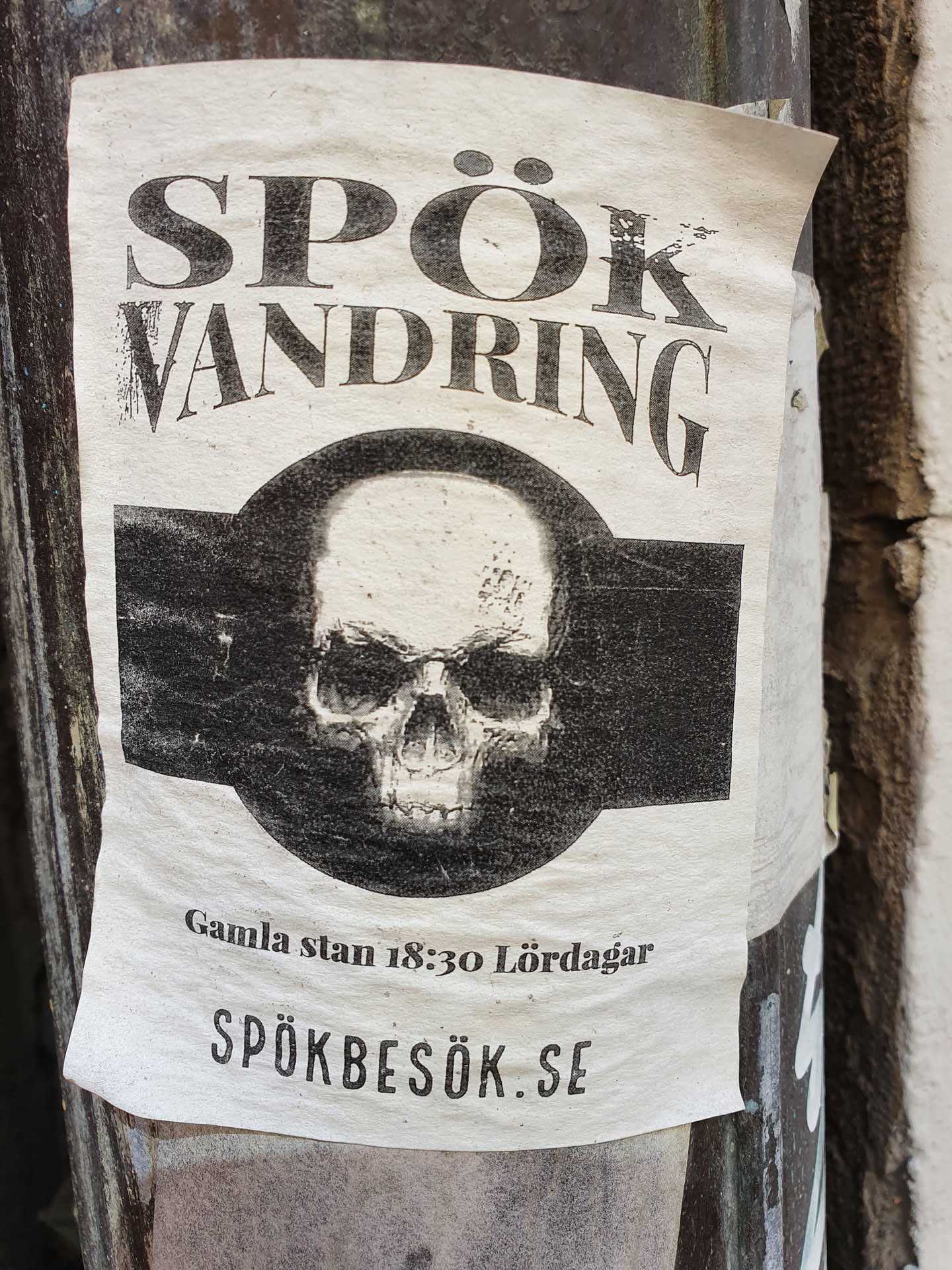 A sticker advertising a ghost walk in Gamla Stan, Stockholm. The sticker features a skull and the website spökbesök.se.