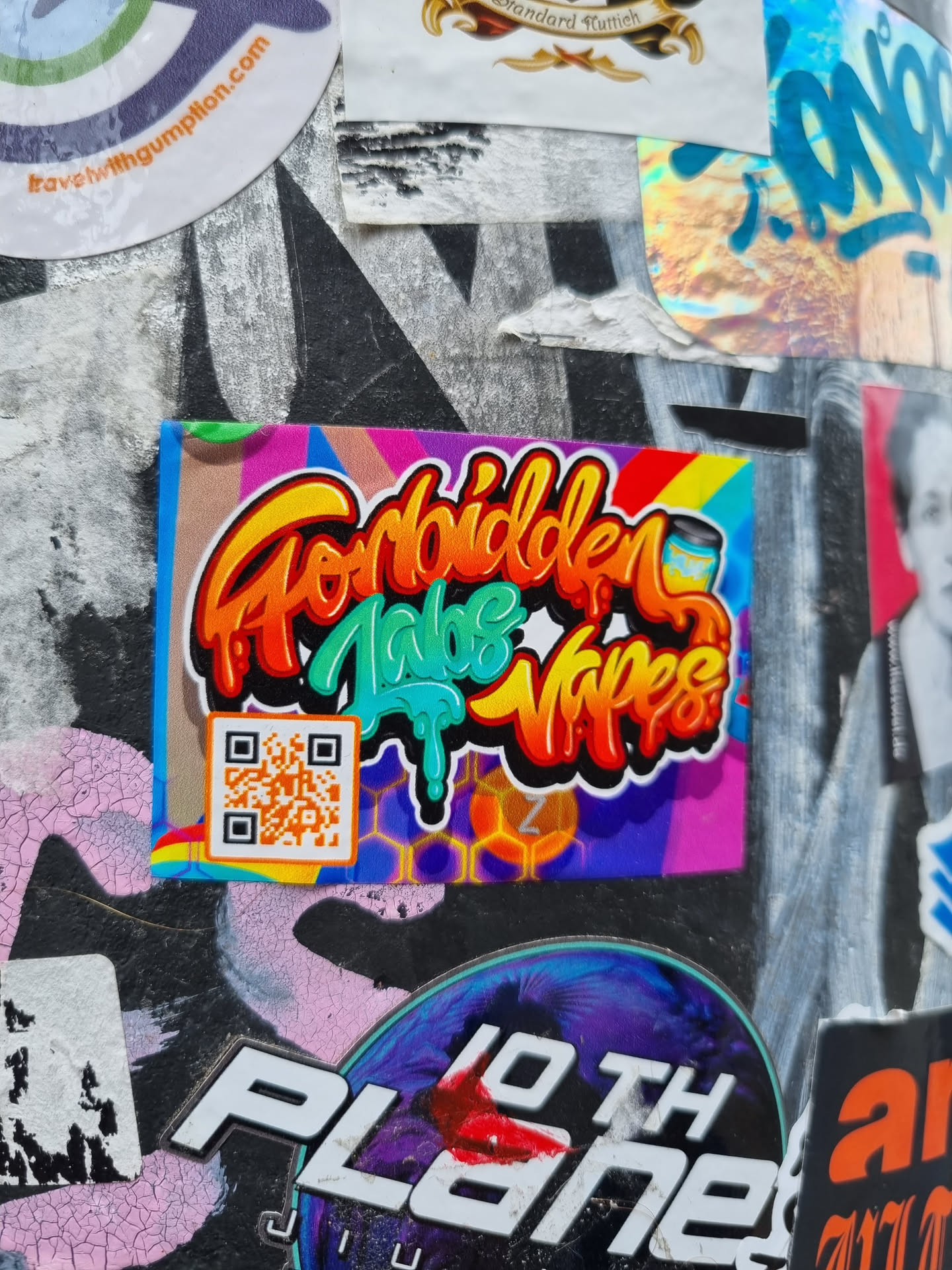A colorful sticker with graffiti-style text that says "Forbidden Vape Vibes." It features a QR code and a honeycomb pattern. The sticker is vibrant and eye-catching.