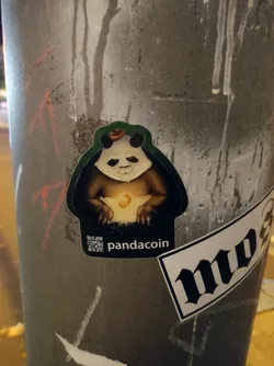 A sticker featuring a cartoon panda wearing a hat and holding a moon. The text 'pandacoin' is visible at the bottom of the sticker, along with a QR code. 