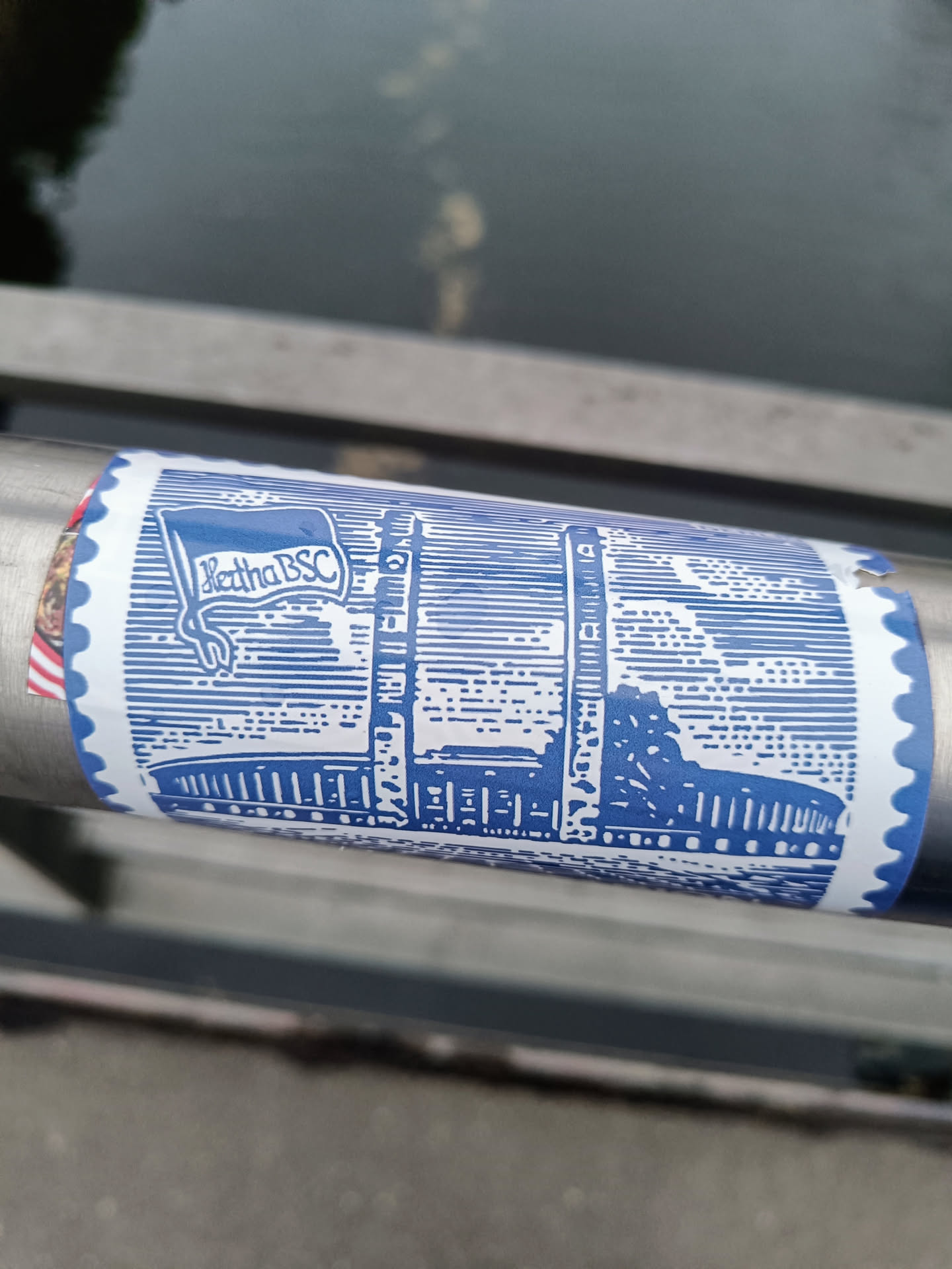 A blue and white sticker featuring an illustration of what appears to be a building or landmark, along with the text 'Ketha BSC'. It's designed to resemble a postage stamp. 