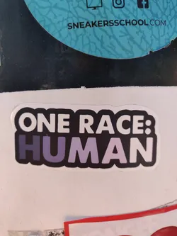 A sticker with the text "ONE RACE: HUMAN" in black and purple. The background is white. 