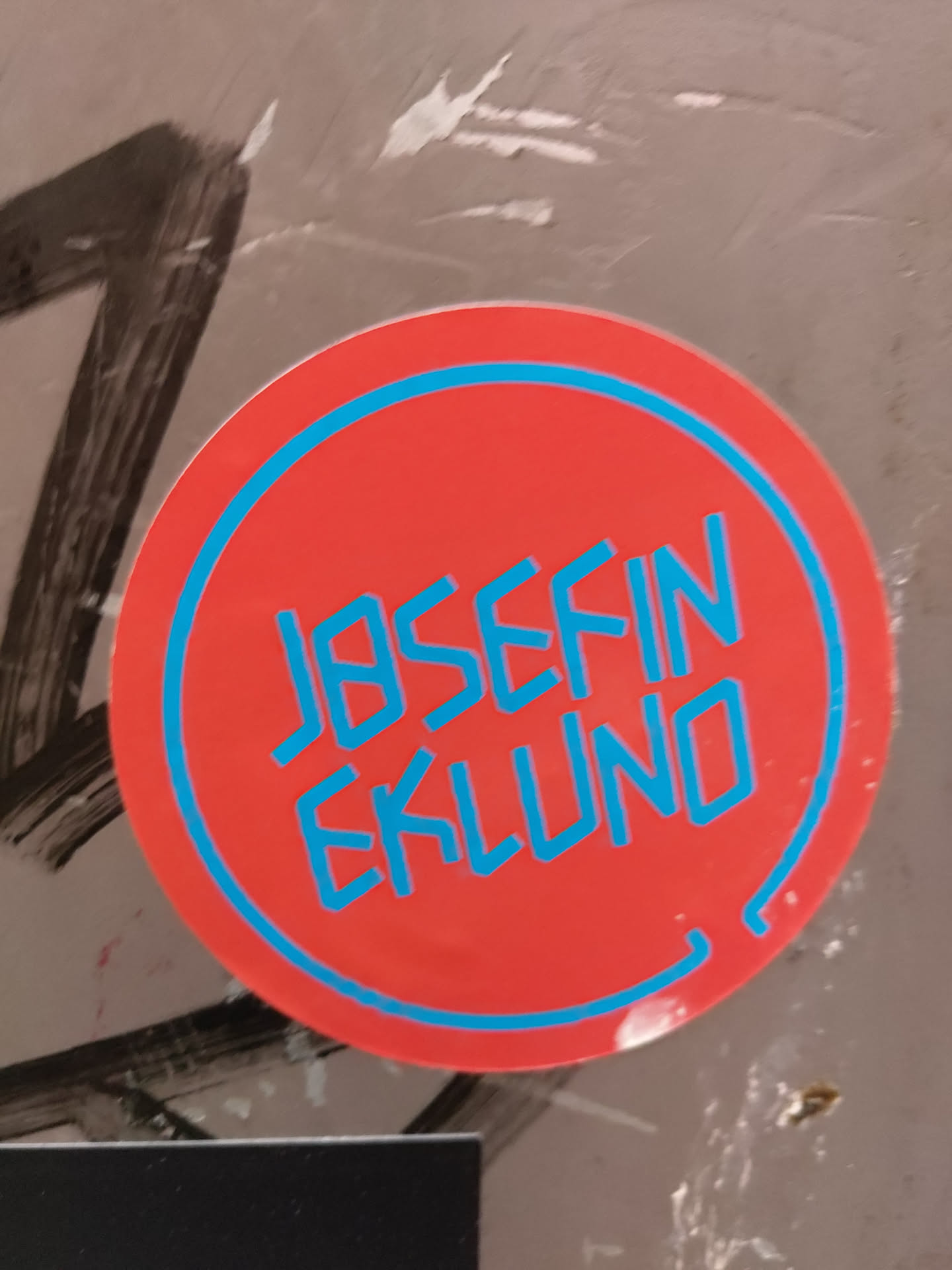 Round red sticker with a teal border. The name JOSEFIN EKLUND is written in a stylized teal font.