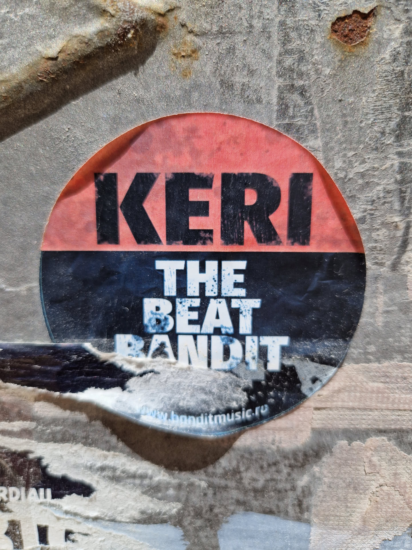 Round sticker with the text "KERI" on top in large, bold, black letters on a pinkish-red background, and "THE BEAT BANDIT" below in smaller, white, bold letters on a black background.  A website address is visible at the bottom. 